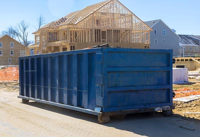 an open-top trash container being loaded onto a dump truck